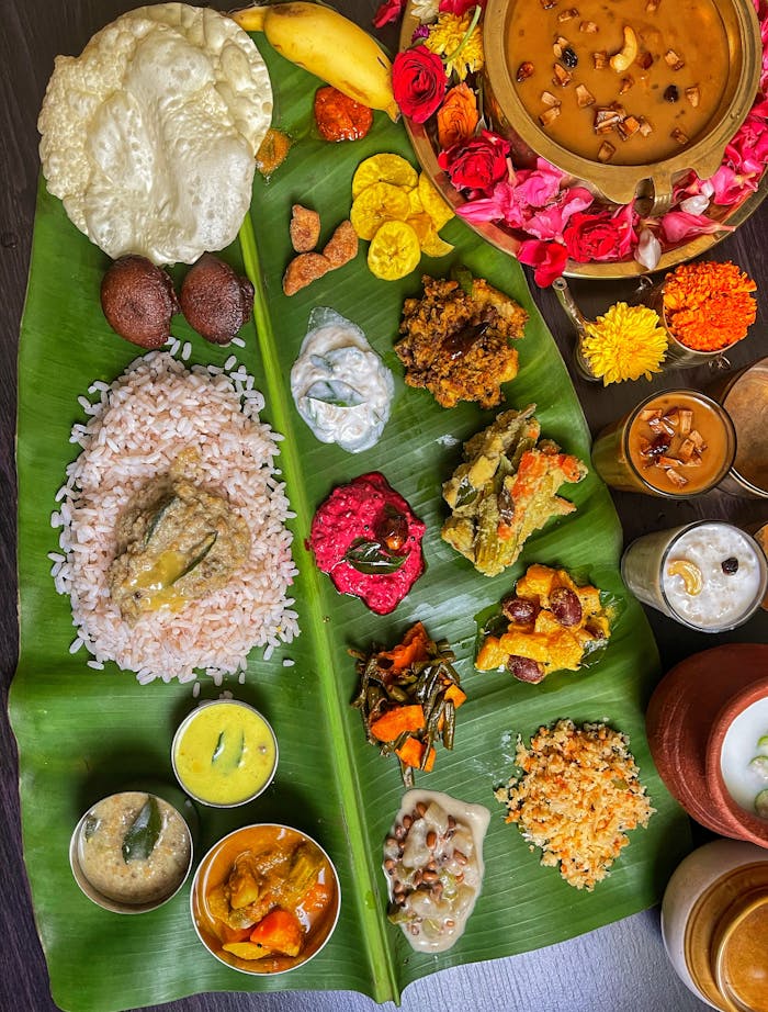 An elaborate South Indian meal with various dishes artfully arranged on a banana leaf, showcasing vibrant colors and textures.